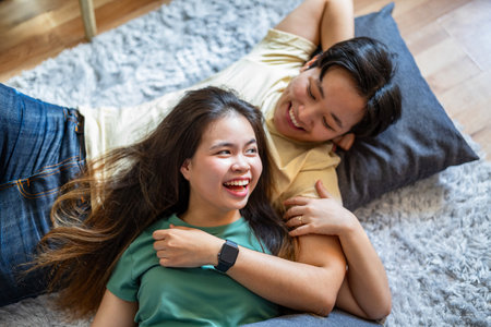 Happy asian young couple lying on the floor in the living roomの写真素材