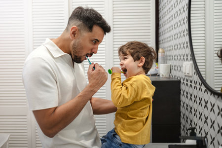 Father and son brushing teeth in the bathroom. Hygiene concept.