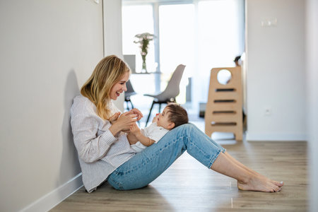Mother and daughter sitting on the floor in the living room at homeの写真素材