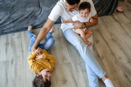 Top view of happy young Caucasian family with two children sitting on floor at home.の写真素材