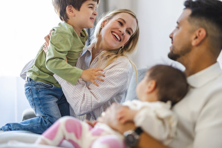 Happy young family with two children sitting on sofa in living room at homeの写真素材