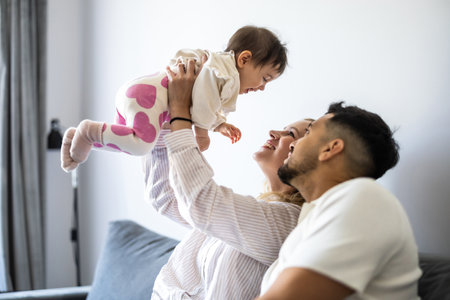Happy young family playing together at home. Mother, father and their little daughter having fun together.の写真素材