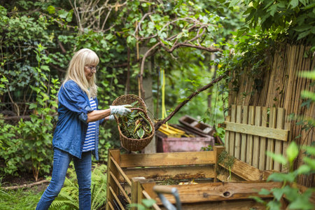Senior woman gardening in her garden, she is holding a basket with plants