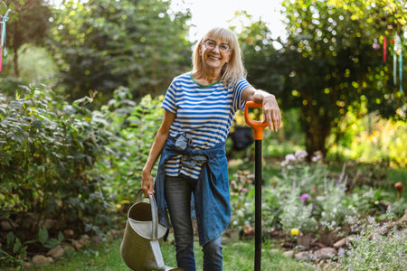 Portrait of smiling senior woman with gardening tools in the garden.の写真素材