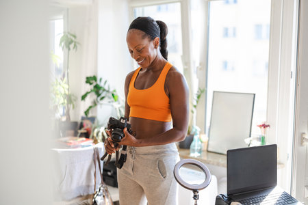 Front view of a fit young African American woman taking a photo at homeの写真素材