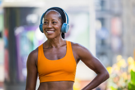 Portrait of happy african american woman listening to music in earphones at streetの写真素材