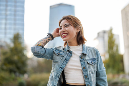 Portrait of a smiling young woman in denim jacket posing in the cityの写真素材