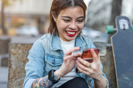 Beautiful young woman using mobile phone in the streetの写真素材