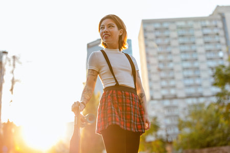 Young hipster woman with skateboard in the city at sunset.の写真素材