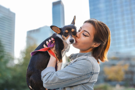 Beautiful young woman kissing her dog in the cityの写真素材