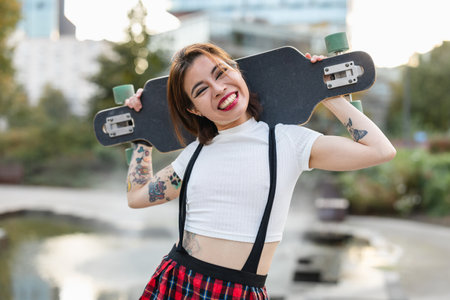Portrait of a smiling young woman with skateboard in the cityの写真素材