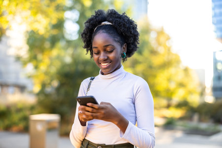 Portrait of young african american woman using mobile phone in the cityの写真素材