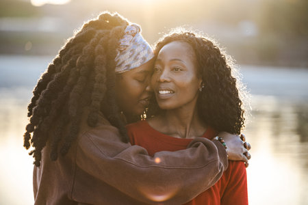Portrait of two young women embracing each other in park at sunsetの写真素材