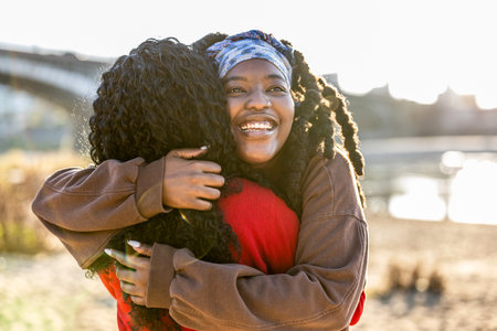 Portrait of smiling african american woman hugging her friend outdoorsの写真素材