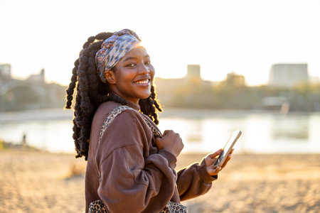 Portrait of a young African woman using mobile phone on the beachの写真素材