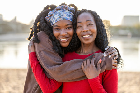 portrait of two african american women hugging on the beachの写真素材