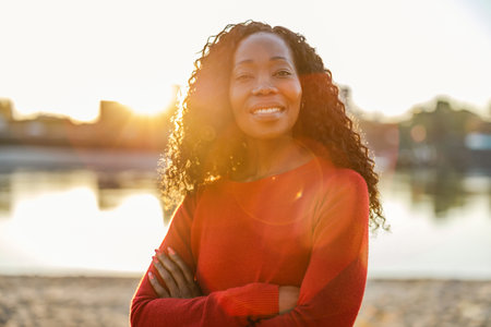 Portrait of a smiling african american woman standing with arms crossed outdoorsの写真素材