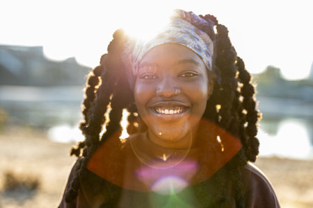 Portrait of smiling african american woman with dreadlocks at sunsetの写真素材