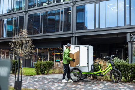 side view of delivery man holding carton boxes near electric scooterの写真素材