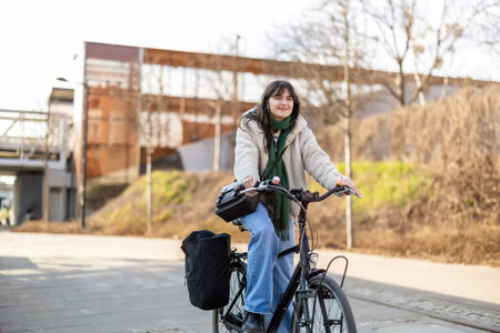 Beautiful young brunette woman riding a bicycle in the city.の写真素材