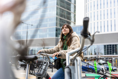 Young brunette woman in beige coat and jeans with bicycle in the cityの写真素材