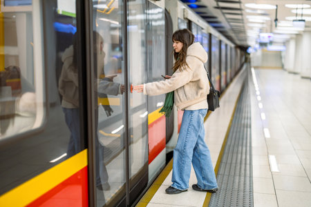 Young woman using mobile phone while waiting for train at subway station.