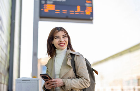 Young woman using her mobile phone at the train station.の写真素材