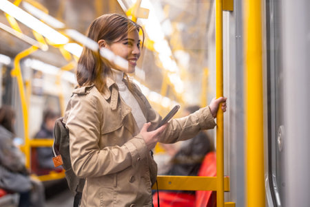 Young woman using mobile phone while traveling by subwayの写真素材