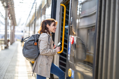 Young woman waiting for a train at the platform of a train stationの写真素材