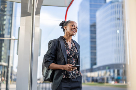Portrait of smiling mature African businesswoman using mobile phone in cityの写真素材