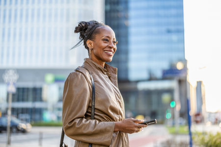 Portrait of smiling african american woman using mobile phone in cityの写真素材
