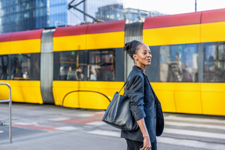 Young businesswoman walking on the street with a train in the backgroundの写真素材