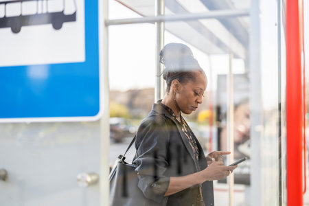 Mature african american woman using mobile phone in bus stopの写真素材