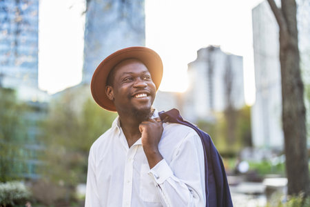 Handsome african american man in hat and shirt posing in the cityの写真素材