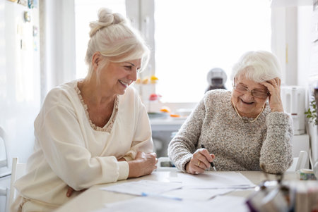 Smiling senior woman with her caregiver at the table in the kitchenの写真素材