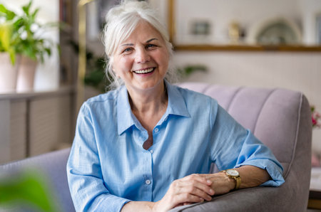 Portrait of smiling senior woman sitting in armchair at home.