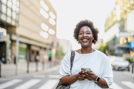 Portrait of smiling african american woman using mobile phone in cityの写真素材