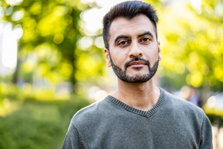 Portrait of handsome bearded Indian man in the park. Looking at camera.の写真素材