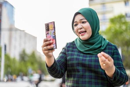 Portrait of happy young muslim woman taking selfie with mobile phone