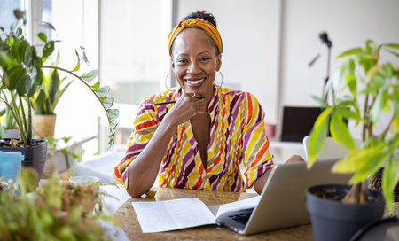 Portrait of smiling mature woman using laptop while sitting at table in office