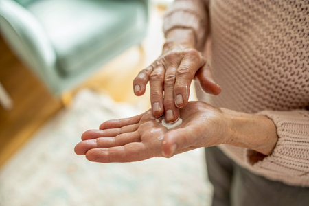 Elderly woman applying cream on her hands.の写真素材