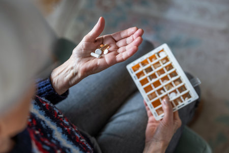 Close up of senior woman taking pills at home, focus on handの写真素材