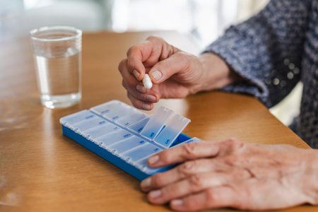 Senior woman using a pill organizer. Focus on the hand.