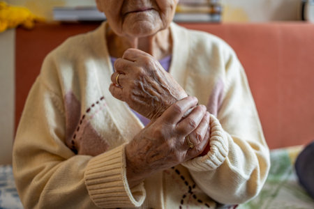 Elderly woman holding her hands together in a retirement home.