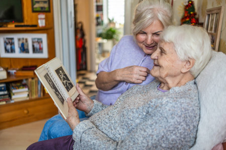 Senior woman looking at old photos with her caregiver