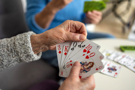 Elderly woman playing cards at home, focus on the handsの写真素材