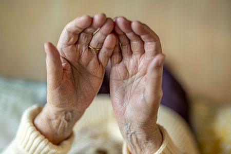 Old woman's hands holding a golden wedding ring. Focus on hands.の写真素材