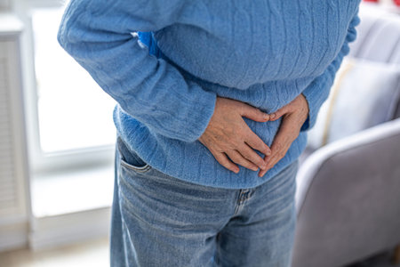 Mid section of person suffering from stomachache at home in the living room