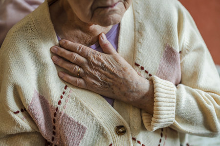 Elderly woman holding her hands on her chest, close up