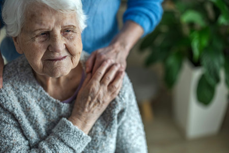 Close up of senior woman sitting in armchair with her caregiver
